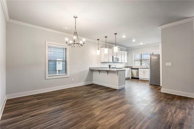 kitchen featuring a breakfast bar area, baseboards, a peninsula, dark wood-style flooring, and stainless steel appliances