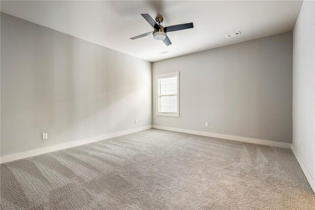 carpeted spare room with visible vents, baseboards, and ceiling fan