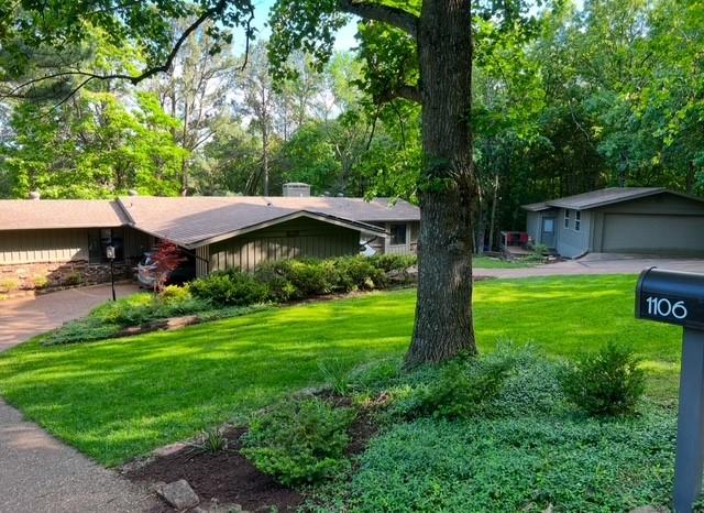 ranch-style home featuring a garage, a front lawn, and an outbuilding