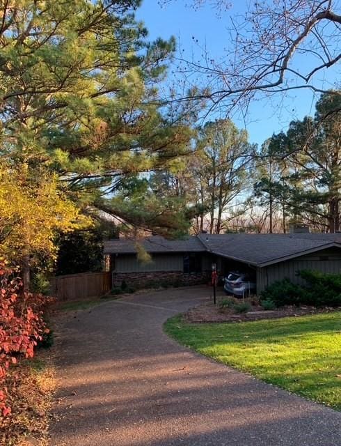 view of front facade featuring aphalt driveway, stone siding, and a front lawn