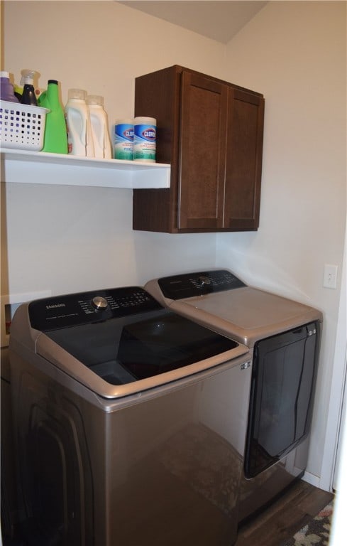 clothes washing area with wood finished floors, cabinet space, and washer and dryer