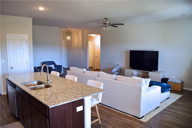 kitchen featuring a breakfast bar area, dark wood-type flooring, a sink, a kitchen island with sink, and stainless steel dishwasher