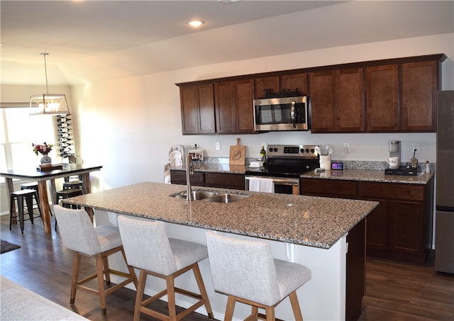 kitchen with stainless steel appliances, a breakfast bar area, a sink, and dark wood finished floors