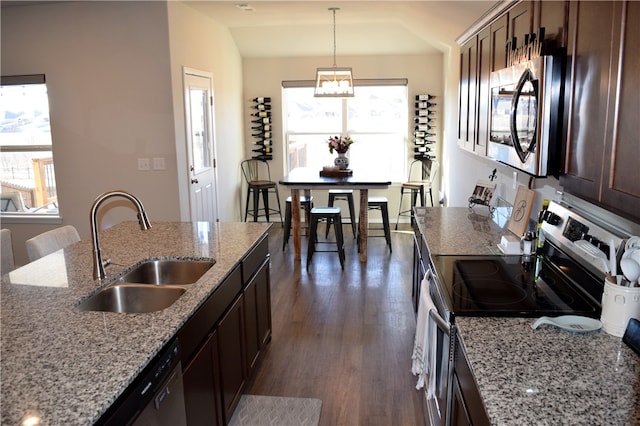 kitchen featuring dark wood finished floors, appliances with stainless steel finishes, decorative light fixtures, vaulted ceiling, and a sink