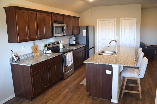 kitchen featuring a breakfast bar, a center island with sink, stainless steel appliances, dark wood-type flooring, and a sink