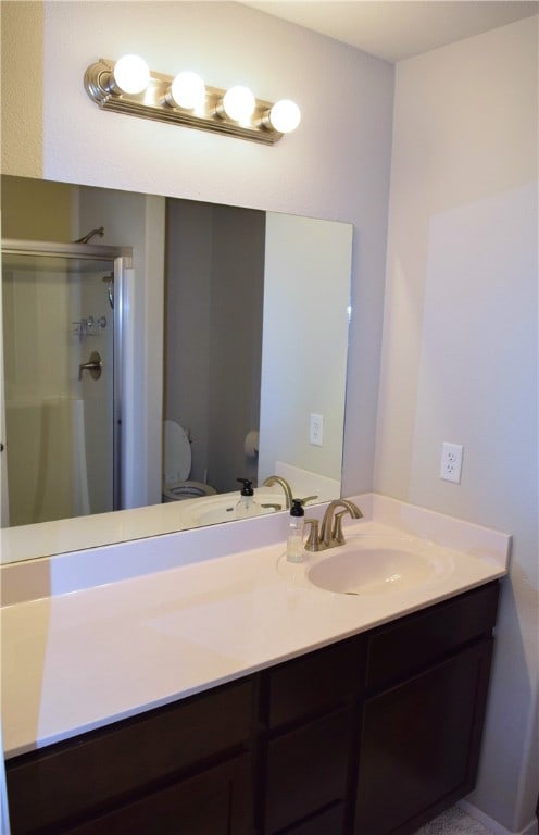 bathroom with a stall shower, vanity, and toilet