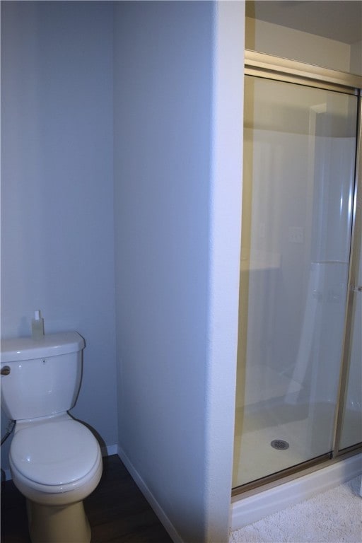 full bath with toilet, a stall shower, and baseboards