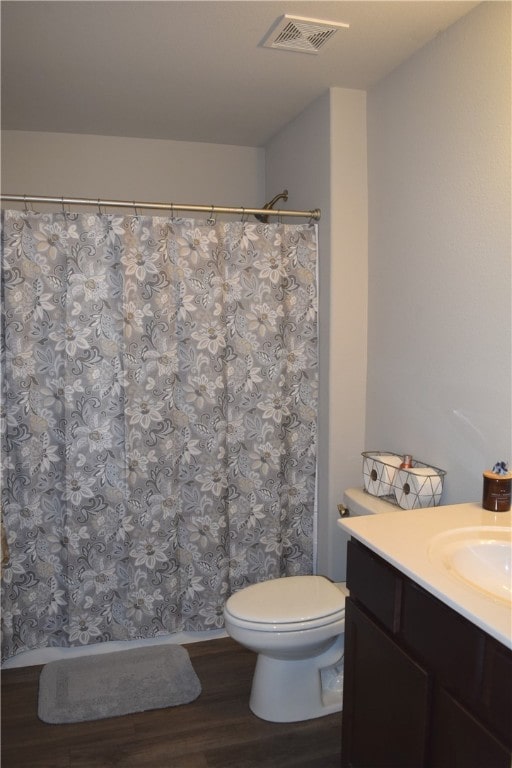 full bath with visible vents, a shower with shower curtain, toilet, vanity, and wood finished floors