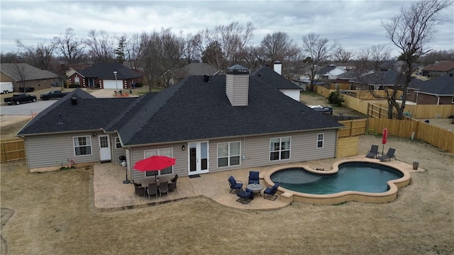 rear view of property featuring a fenced in pool, a patio, a fenced backyard, a residential view, and roof with shingles