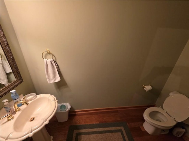 bathroom with toilet, baseboards, a sink, and wood finished floors