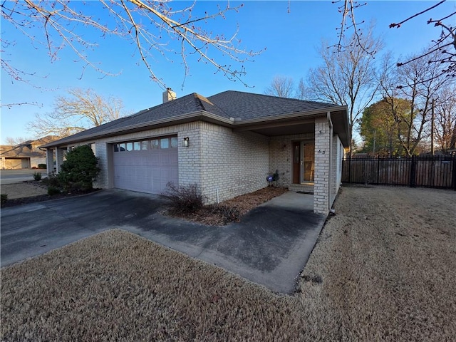 view of front of property with driveway, a garage, a chimney, fence, and brick siding