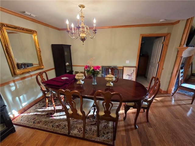 dining room with a chandelier, wood finished floors, visible vents, baseboards, and crown molding