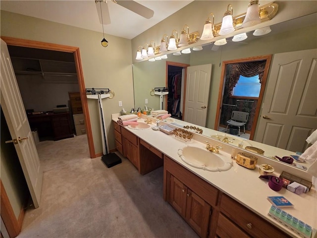 full bathroom with ceiling fan, double vanity, a spacious closet, and a sink