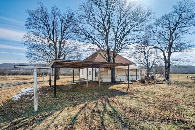 view of yard featuring a detached carport and dirt driveway