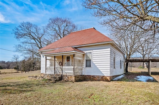 view of front of property with covered porch, a carport, roof with shingles, and a front yard