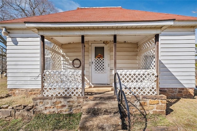 property entrance featuring covered porch and roof with shingles