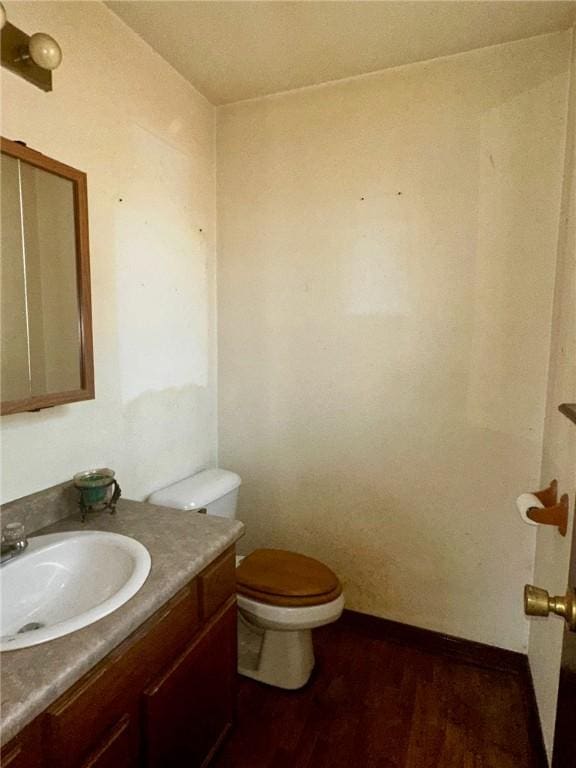 bathroom with vanity, wood finished floors, toilet, and baseboards