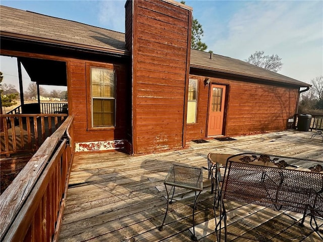 rear view of property with roof with shingles, a chimney, and a wooden deck