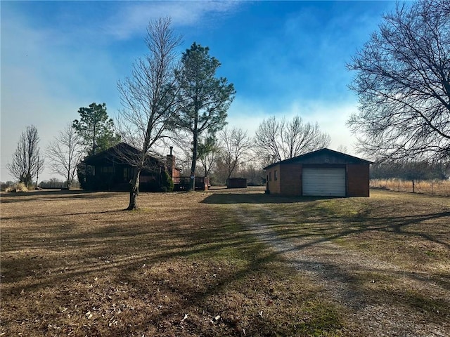 view of yard featuring an outbuilding, a detached garage, and dirt driveway