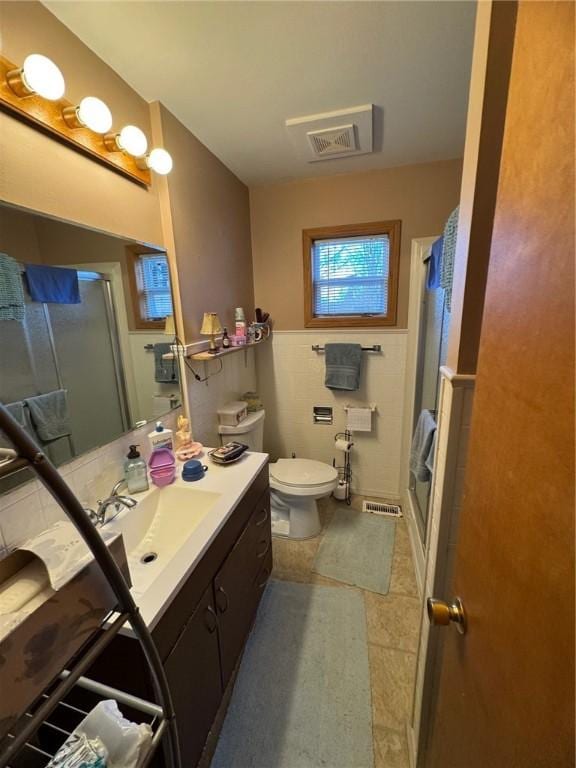 bathroom with visible vents, toilet, a shower stall, and vanity