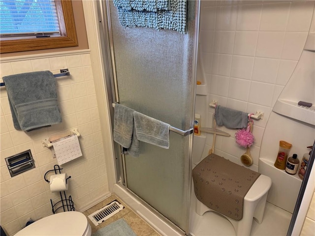 bathroom featuring visible vents, toilet, a shower stall, and tile walls