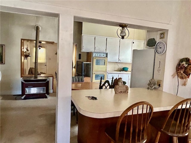 kitchen with a wood stove, double wall oven, light countertops, and freestanding refrigerator