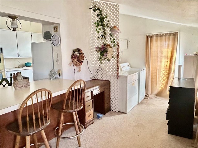 interior space featuring lofted ceiling, light countertops, a kitchen bar, and washing machine and clothes dryer