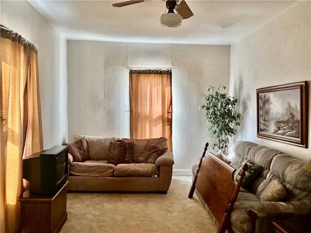 living area featuring light carpet and a ceiling fan