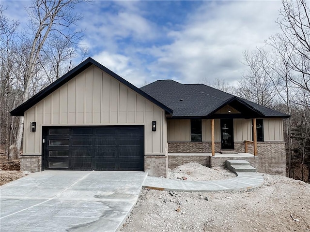 view of front facade with a garage, brick siding, a shingled roof, concrete driveway, and board and batten siding