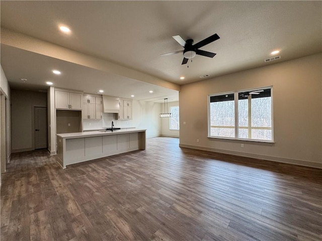 unfurnished living room with dark wood finished floors, recessed lighting, visible vents, a ceiling fan, and baseboards