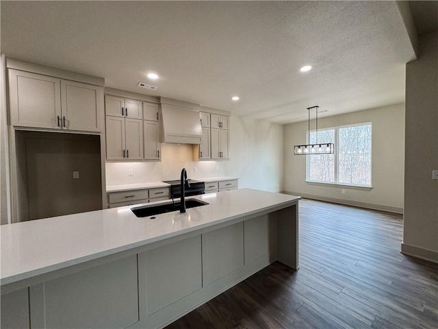 kitchen with recessed lighting, premium range hood, dark wood-type flooring, a sink, and light countertops