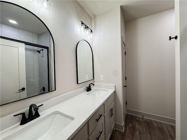 full bath featuring double vanity, wood finished floors, tiled shower, and a sink