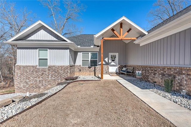 exterior space featuring brick siding, a patio area, and a shingled roof