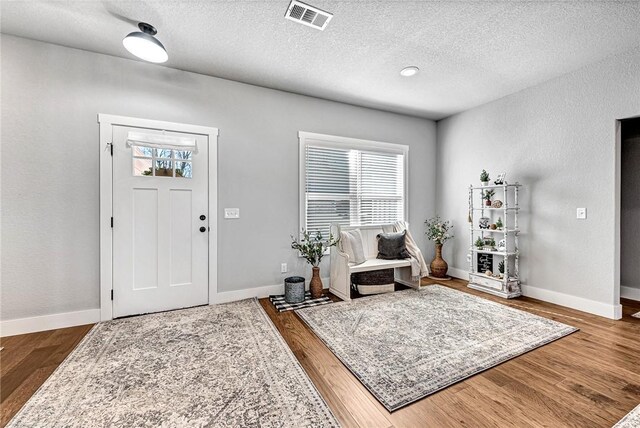 foyer featuring visible vents, a healthy amount of sunlight, and wood finished floors