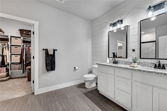 full bath featuring a sink, a walk in closet, toilet, and double vanity