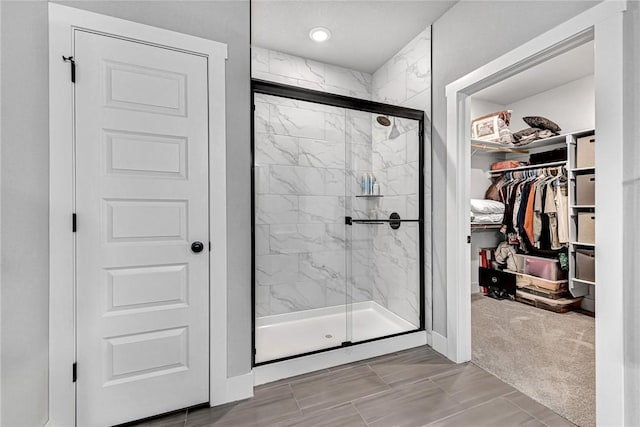 bathroom featuring a marble finish shower and a walk in closet