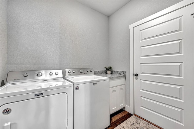 clothes washing area with cabinet space, independent washer and dryer, dark wood finished floors, and a textured wall