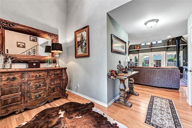 corridor featuring french doors, baseboards, and wood finished floors