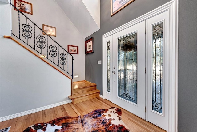 foyer entrance with baseboards, visible vents, stairway, and wood finished floors