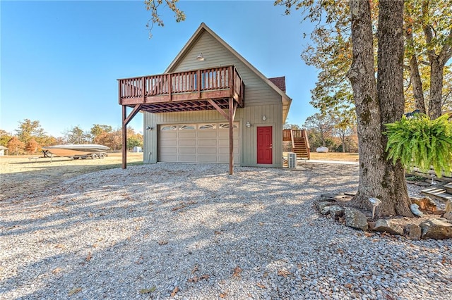 view of front of home with central air condition unit, a garage, driveway, a wooden deck, and stairs