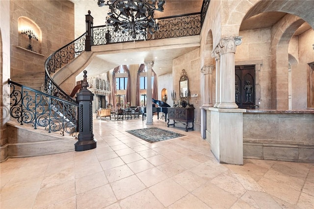 2 S Samoset Ct, Rogers, AR 72758 - entryway featuring a towering ceiling, a chandelier, stairway, decorative columns, and stone tile flooring