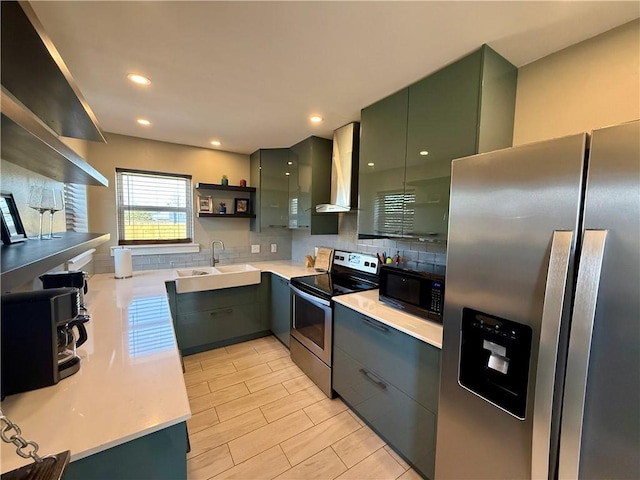 kitchen featuring open shelves, a sink, green cabinets, appliances with stainless steel finishes, and wall chimney exhaust hood