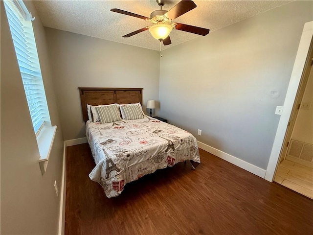 bedroom featuring baseboards, a textured ceiling, visible vents, and wood finished floors