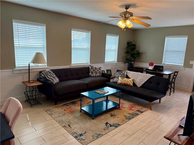 living room with wood finish floors, wainscoting, and a ceiling fan