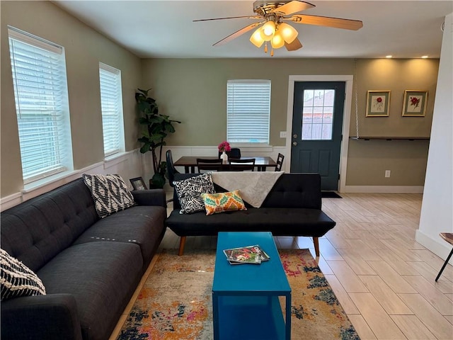 living area featuring ceiling fan, wood finished floors, and wainscoting