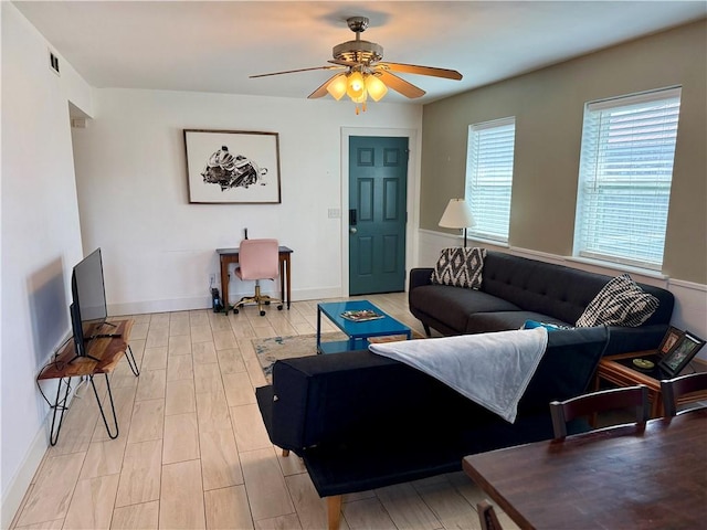 living area featuring baseboards, visible vents, light wood-style flooring, and a ceiling fan