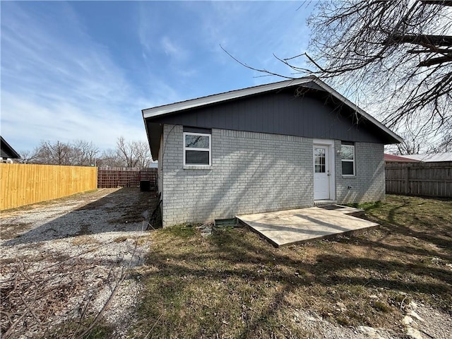 rear view of property featuring a patio area, brick siding, and fence