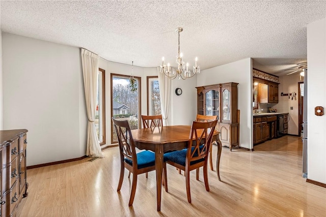 dining area featuring light wood-type flooring, a textured ceiling, baseboards, and ceiling fan with notable chandelier