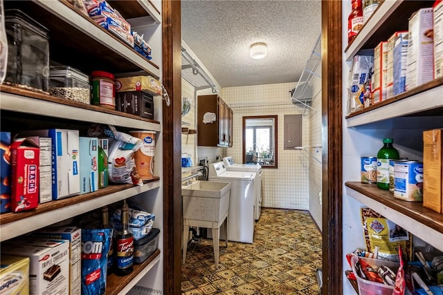 washroom featuring a textured ceiling, independent washer and dryer, a sink, and wallpapered walls