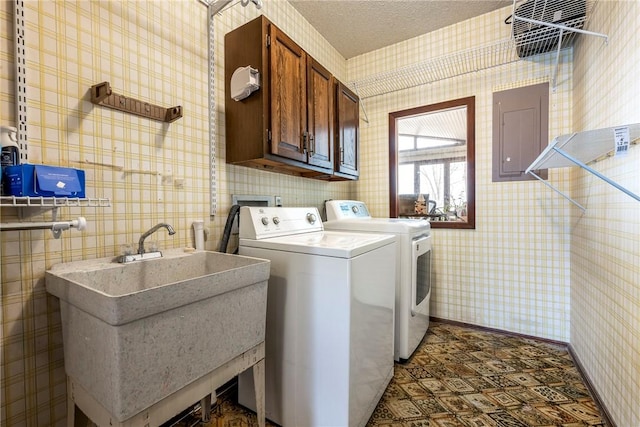 clothes washing area with a textured ceiling, a sink, independent washer and dryer, cabinet space, and wallpapered walls